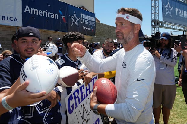 Dallas Cowboys coach Brian Schottenheimer signs autographs at training camp at the River Ridge Fields. 