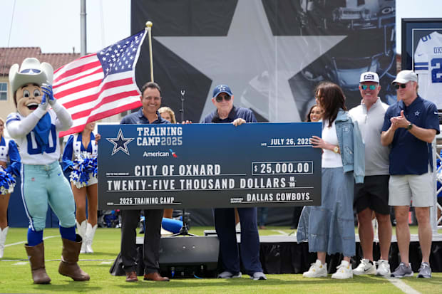 Dallas Cowboys owner Jerry Jones presents Oxnard mayor Luis McArthur with a $25,000 check at training camp opening ceremonies