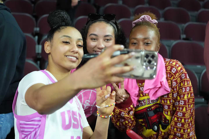 USC women's basketball star guard JuJu Watkins poses for a selfie with fans after the game against Michigan State.