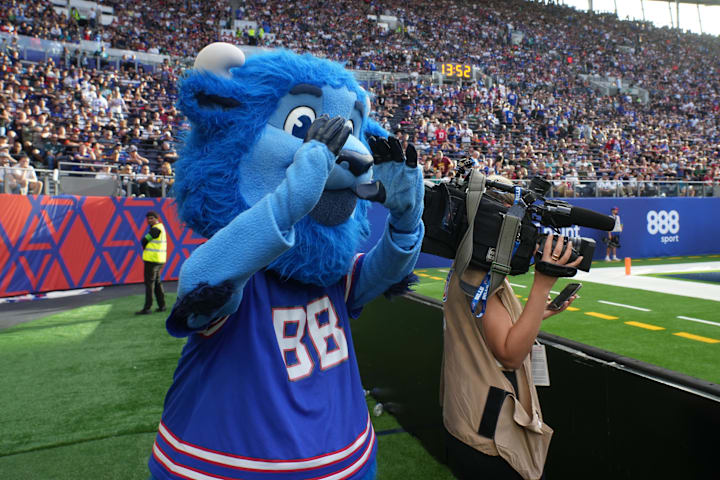 Buffalo Bills mascot Billy Buffalo interacts with WHAM TV camera person Jenna Cottrell during an NFL International Series gam