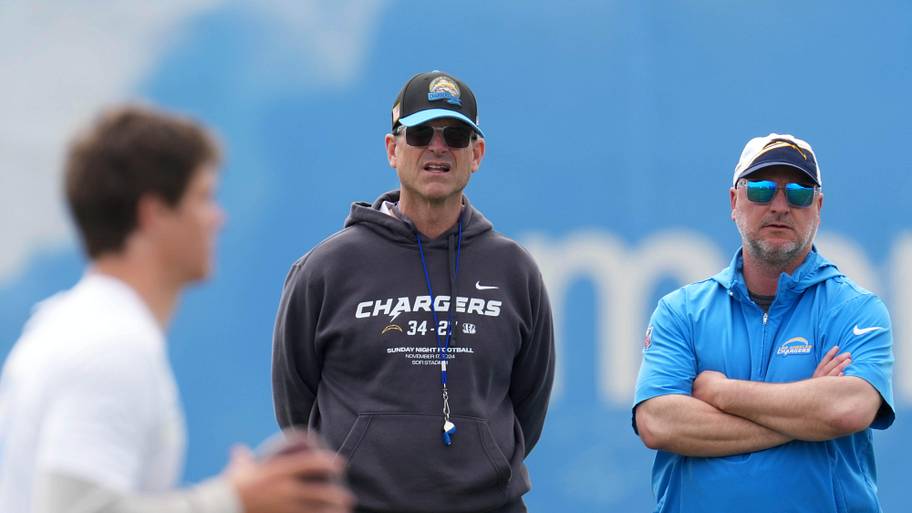 Los Angeles Chargers coach Jim Harbaugh and general manager Joe Hortiz watch as quarterback Justin Herbert throws.