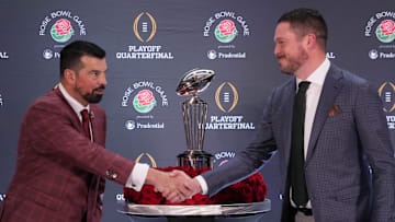 Dec 31, 2024; Los Angeles, California, USA; Ohio State Buckeyes head coach Ryan Day (left) and Oregon Ducks head coach Dan Lanning shake hands with the Leishman Trophy as a backdrop during the Rose Bowl head coaches press conference at Sheraton Grand LA. Mandatory Credit: Kirby Lee-Imagn Images