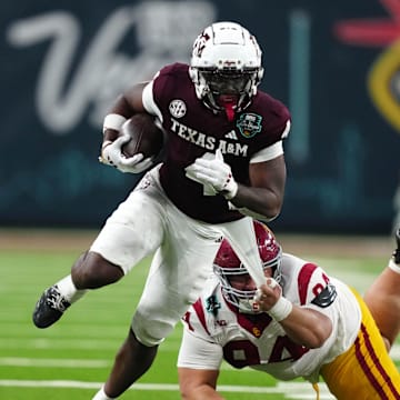 Dec 27, 2024; Las Vegas, NV, USA; Texas A&M Aggies wide receiver Micah Tease (4) carries the ball against Southern California Trojans defensive tackle Kobe Pepe (94) in the second half at Allegiant Stadium. Mandatory Credit: Kirby Lee-Imagn Images