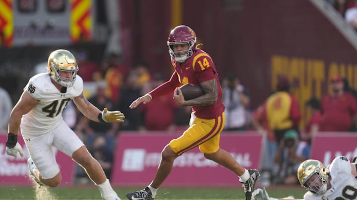 Nov 30, 2024; Los Angeles, California, USA; Southern California Trojans quarterback Jayden Maiava (14) carries the ball against Notre Dame Fighting Irish defensive lineman Joshua Burnham (40) and defensive lineman Rylie Mills (99) in the second half at United Airlines Field at Los Angeles Memorial Coliseum. Mandatory Credit: Kirby Lee-Imagn Images