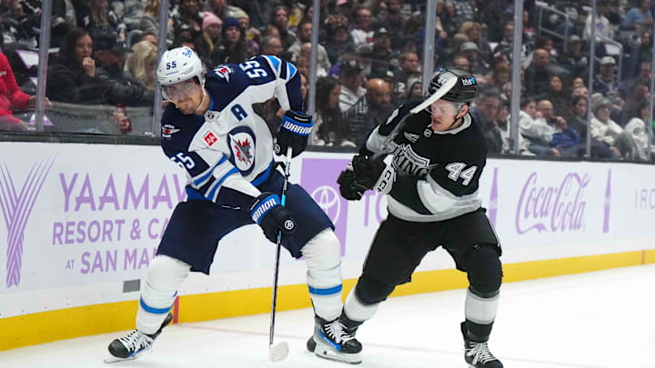 Nov 27, 2024; Los Angeles, California, USA; Winnipeg Jets center Mark Scheifele (55) and LA Kings defenseman Mikey Anderson (44) battle for the puck in the first period at Crypto.com Arena. Mandatory Credit: Kirby Lee-Imagn Images