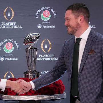 Dec 31, 2024; Los Angeles, California, USA; Ohio State Buckeyes head coach Ryan Day (left) and Oregon Ducks head coach Dan Lanning shake hands with the Leishman Trophy as a backdrop during the Rose Bowl head coaches press conference at Sheraton Grand LA. Mandatory Credit: Kirby Lee-Imagn Images