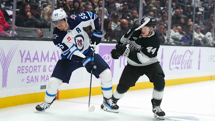 Nov 27, 2024; Los Angeles, California, USA; Winnipeg Jets center Mark Scheifele (55) and LA Kings defenseman Mikey Anderson (44) battle for the puck in the first period at Crypto.com Arena. Mandatory Credit: Kirby Lee-Imagn Images