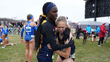 Joy Naukot, who took home a bronze medal at the NCAA Track and Field Championships on Thursday night, huddles with a teammate at a cross country meet.