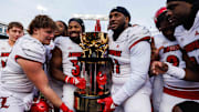 Nov 30, 2024; Lexington, Kentucky, USA; Louisville Cardinals defensive lineman Ramon Puryear (41) and Louisville Cardinals defensive back Jathan Hatch (31) hold up the Governor’s Cup trophy after winning against the Kentucky Wildcats at Kroger Field. Mandatory Credit: Jordan Prather-Imagn Images