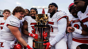 Nov 30, 2024; Lexington, Kentucky, USA; Louisville Cardinals defensive lineman Ramon Puryear (41) and Louisville Cardinals defensive back Jathan Hatch (31) hold up the Governor’s Cup trophy after winning against the Kentucky Wildcats at Kroger Field. Mandatory Credit: Jordan Prather-Imagn Images