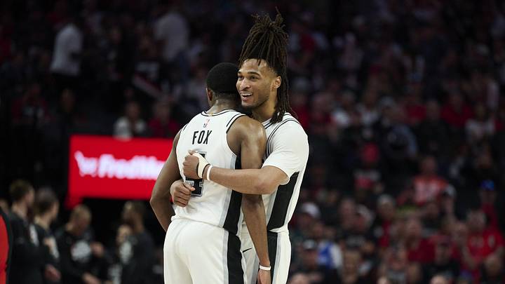 Apr 26, 2026; Portland, Oregon, USA; San Antonio Spurs guard Stephon Castle (5) embraces guard De'aaron Fox (4) during the second half in a game against the Portland Trail Blazers during game four of the first round of the 2026 NBA Playoffs at Moda Center. Mandatory Credit: Troy Wayrynen-Imagn Images