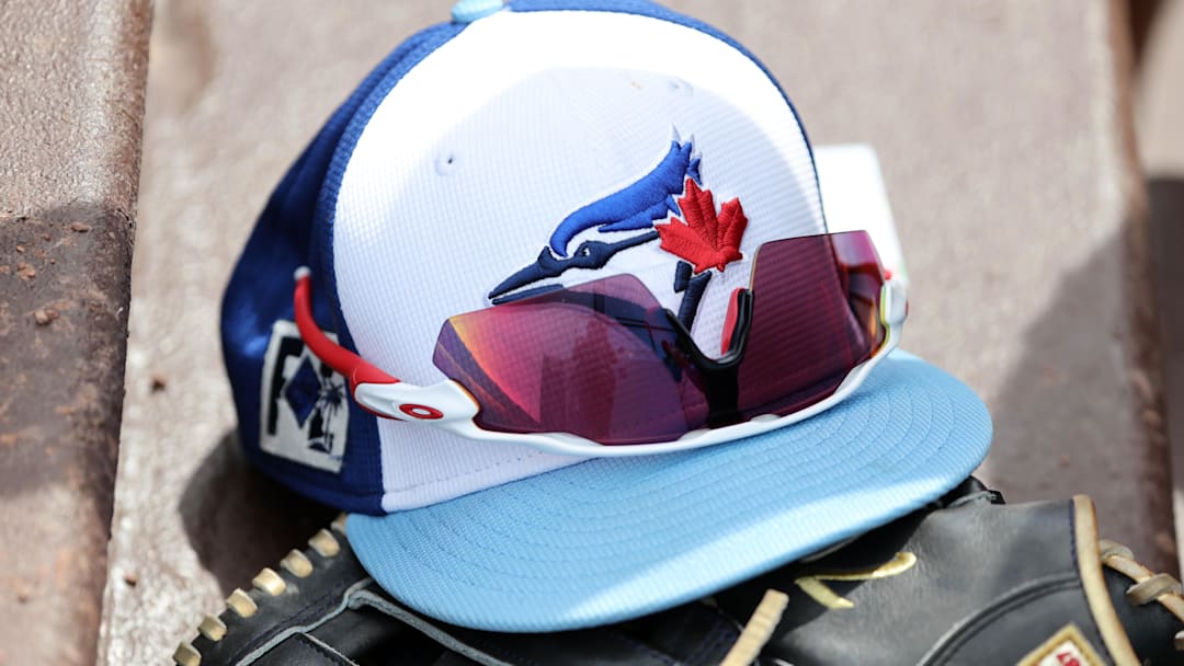 Mar 1, 2025; North Port, Florida, USA;  A detail view of a Toronto Blue Jays hat , sunglasses and glove laying in the dugout against the Atlanta Braves at CoolToday Park. 