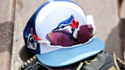 Mar 1, 2025; North Port, Florida, USA;  A detail view of a Toronto Blue Jays hat , sunglasses and glove laying in the dugout against the Atlanta Braves at CoolToday Park.