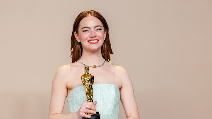 Emma Stone carrying an Oscars statue