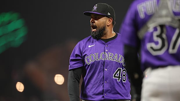 Colorado Rockies pitcher German Marquez yells towards the home plate umpire, wearing a purple jersey and a black hat. 