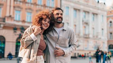 Happy couple embracing and smiling while sightseeing in a city