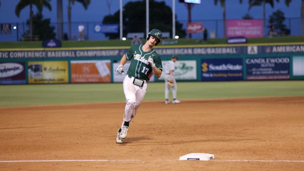 A baseball player in a green jersey rounds the bases.