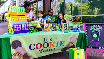 Daisy Girl Scouts and a leader selling at a cookie booth.
