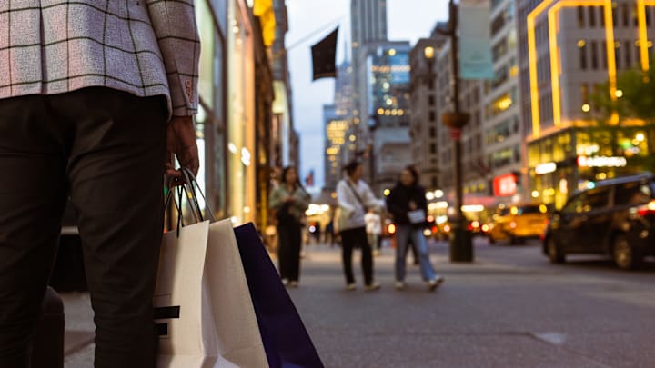 Fifth Avenue in Midtown Manhattan comes alive at night with shoppers and city lights.