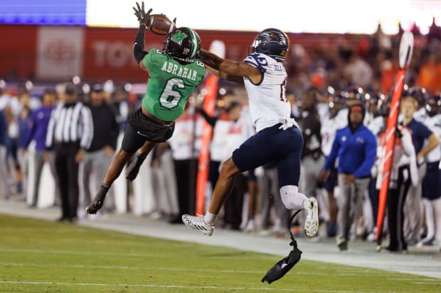 Football player Micah Abraham intercepts a pass in a green jersey.