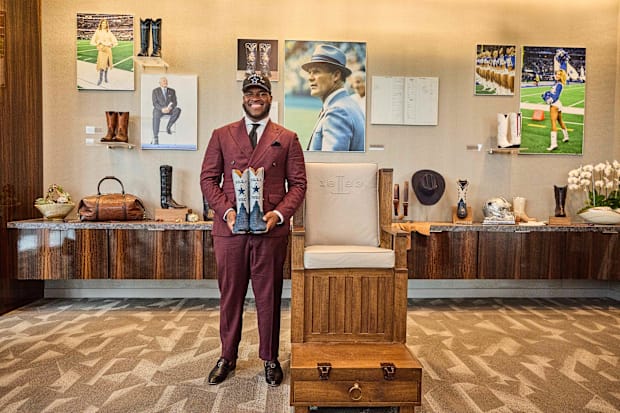 Tyler Booker smiles with a pair of Dallas Cowboys-themed boots.
