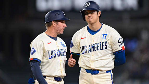 Los Angeles Dodgers designated hitter Shohei Ohtani chats with first base coach Clayton McCullough.
