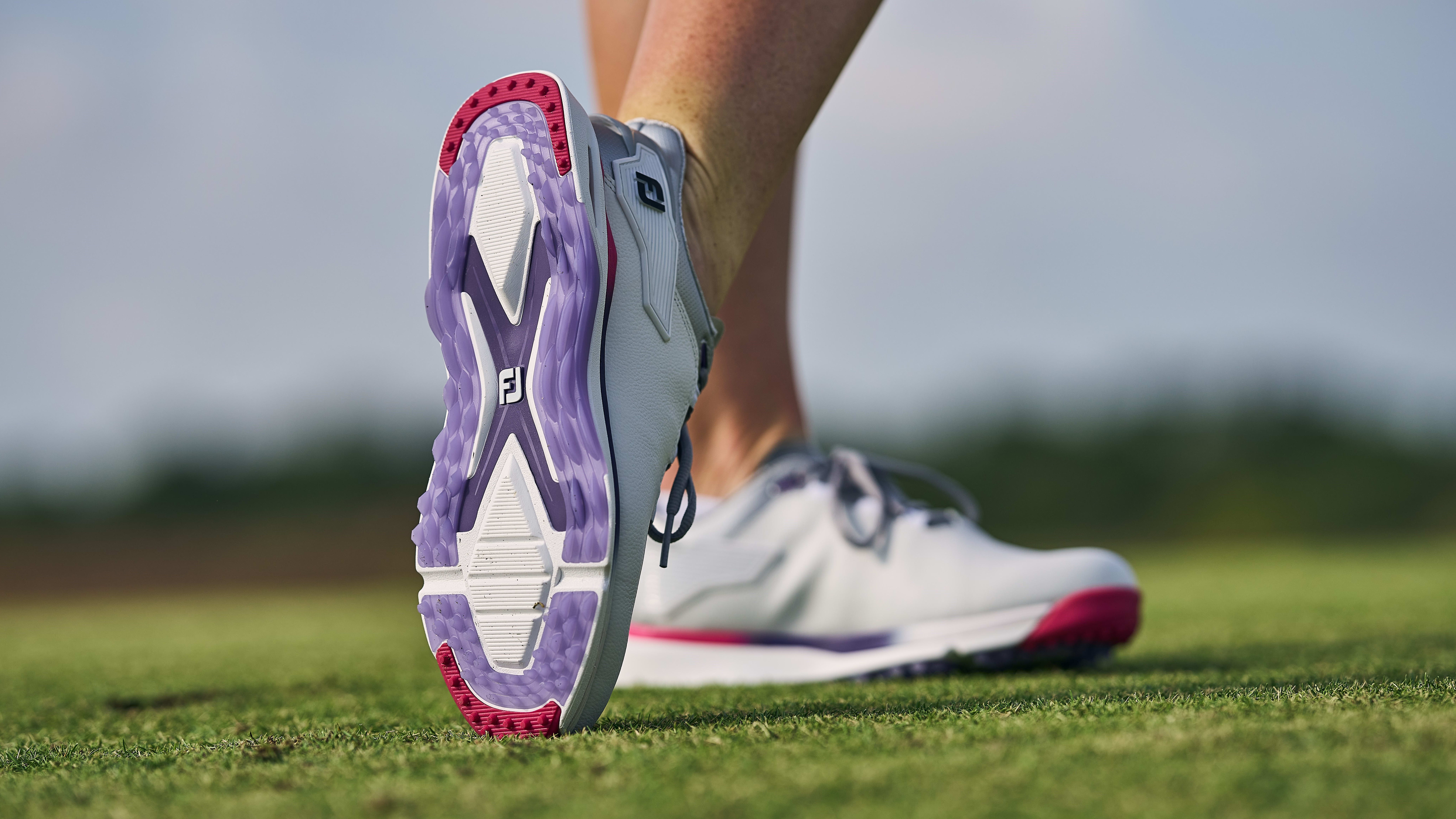 Side view of white and purple FootJoy golf shoes.