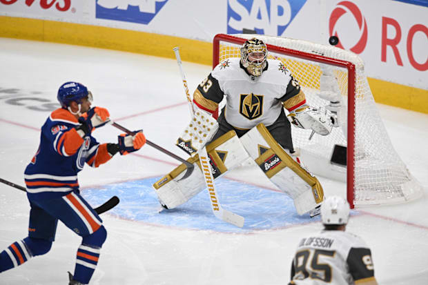 Hockey goalie watches for puck as player tries to shoot i