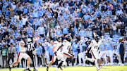 Oct 25, 2025; Chapel Hill, North Carolina, USA;  Virginia Cavaliers players celebrate after stopping North Carolina Tar Heels short of the goal line on a two point try to win in overtime at Kenan Stadium. 