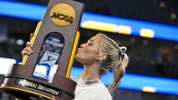 Apr 20, 2024; Fort Worth, TX, USA; LSU Tigers gymnast Olivia Dunne kisses the trophy after the LSU Tigers gymnastics team wins the national championship in the 2024 Womens National Gymnastics Championship at Dickies Arena. Mandatory Credit: Jerome Miron-USA TODAY Sports