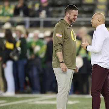 Nov 14, 2025; Eugene, Oregon, USA; Oregon Ducks head coach Dan Lanning, left, and Minnesota Golden Gophers head coach P.J. Fleck talk before a game at Autzen Stadium. Mandatory Credit: Troy Wayrynen-Imagn Images