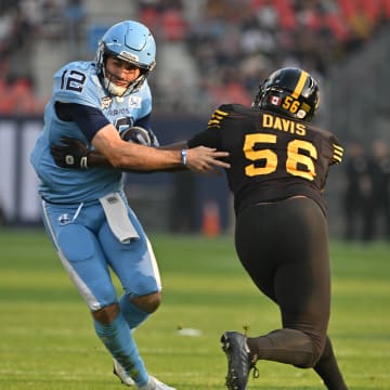 Jun 18, 2023; Toronto, Ontario, CAN;  Toronto Argonauts quarterback Chad Kelly (12) runs past Hamilton Tiger-Cats linebacker Gordon Whyte (58) to score a touchdown in the first quarter at BMO Field. Mandatory Credit: Dan Hamilton-USA TODAY Sports