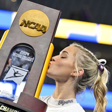 Apr 20, 2024; Fort Worth, TX, USA; LSU Tigers gymnast Olivia Dunne kisses the championship trophy after the LSU Tigers gymnastics team wins the national championship in the 2024 Womens National Gymnastics Championship at Dickies Arena
