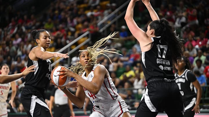 Jul 10, 2025; Washington, District of Columbia, USA; Washington Mystics forward Kiki Iriafen (44) looks to pass the ball between Las Vegas Aces center Kiah Stokes (41) and center Megan Gustafson (17) during the second quarter at EagleBank Arena. Mandatory Credit: Rafael Suanes-Imagn Images