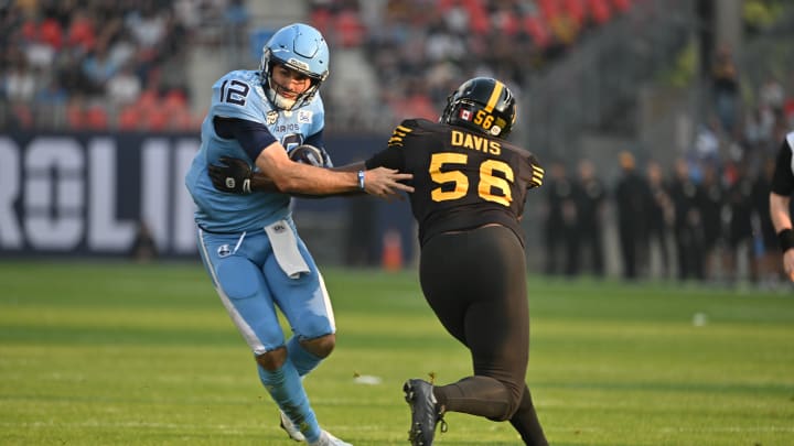 Jun 18, 2023; Toronto, Ontario, CAN;  Toronto Argonauts quarterback Chad Kelly (12) runs past Hamilton Tiger-Cats linebacker Gordon Whyte (58) to score a touchdown in the first quarter at BMO Field. Mandatory Credit: Dan Hamilton-USA TODAY Sports