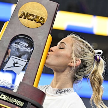 Apr 20, 2024; Fort Worth, TX, USA; LSU Tigers gymnast Olivia Dunne kisses the championship trophy after the LSU Tigers gymnastics team wins the national championship in the 2024 Womens National Gymnastics Championship at Dickies Arena. Mandatory Credit: Jerome Miron-Imagn Images