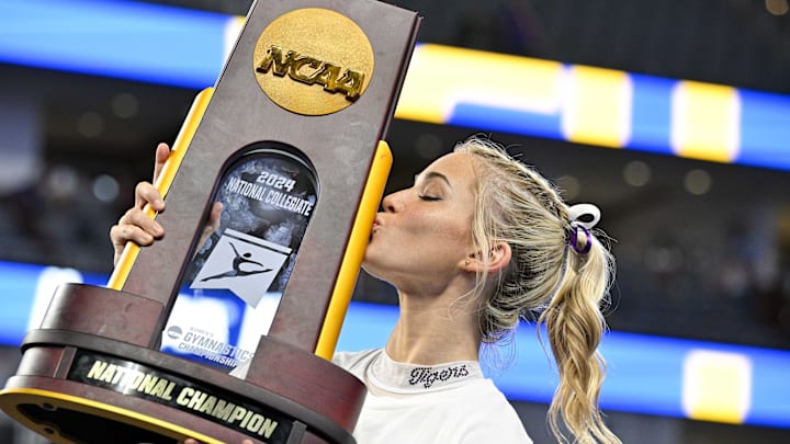 Apr 20, 2024; Fort Worth, TX, USA; LSU Tigers gymnast Olivia Dunne kisses the championship trophy after the LSU Tigers gymnastics team wins the national championship in the 2024 Womens National Gymnastics Championship at Dickies Arena. Mandatory Credit: Jerome Miron-Imagn Images