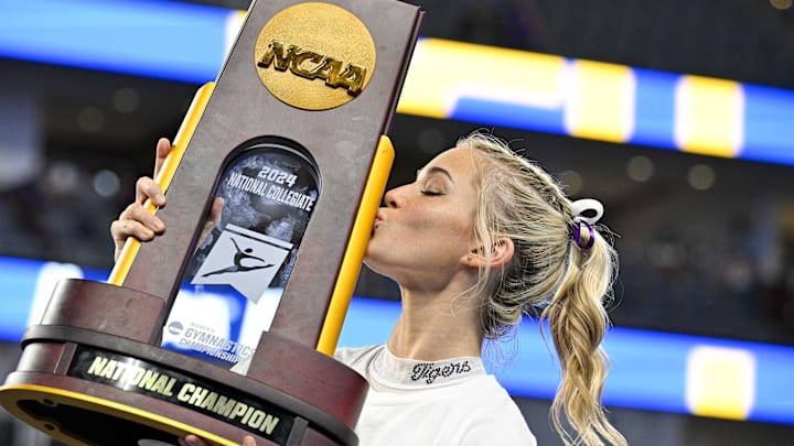 Apr 20, 2024; Fort Worth, TX, USA; LSU Tigers gymnast Olivia Dunne kisses the championship trophy after the LSU Tigers gymnastics team wins the national championship in the 2024 Womens National Gymnastics Championship at Dickies Arena. Mandatory Credit: Jerome Miron-Imagn Images