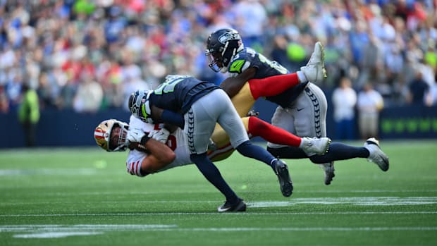 Seahawks cornerback Devon Witherspoon (21) and linebacker Ernest Jones IV (13) tackle 49ers tight end Luke Farrell