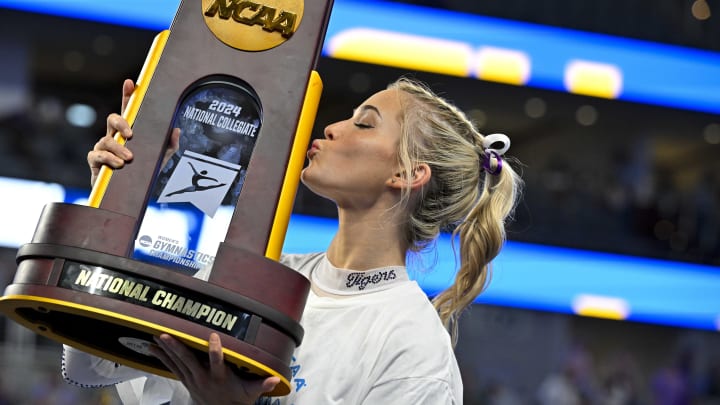 Apr 20, 2024; Fort Worth, TX, USA; LSU Tigers gymnast Olivia Dunne kisses the trophy after the LSU Tigers gymnastics team wins the national championship in the 2024 Womens National Gymnastics Championship at Dickies Arena. Mandatory Credit: Jerome Miron-USA TODAY Sports