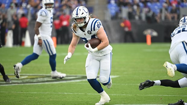 Colts tight end Tyler Warren (blue and white jersey) runs with the ball in open space.