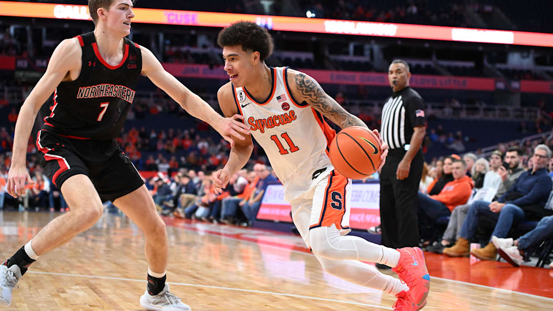 Dec 20, 2025; Syracuse, New York, USA; Syracuse Orange guard Naithan George (11) tries to drive the ball past Northeastern Huskies forward Youri Fritz (7) in the second half at the JMA Wireless Dome. Mandatory Credit: Mark Konezny-Imagn Images