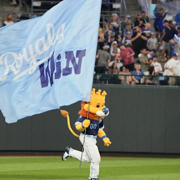 Sep 6, 2024; Kansas City, Missouri, USA; The Kansas City Royals mascot Sluggerrr runs on field with a large flag after the win over the Minnesota Twins at Kauffman Stadium. Mandatory Credit: Denny Medley-Imagn Images