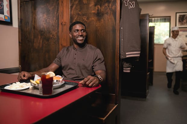 Reggie Bush models golf apparel in a diner.