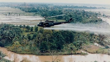 An American Huey helicopter sprays Agent Orange over Vietnam.
