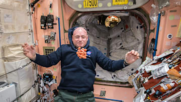 NASA astronaut Scott Kelly watches a bunch of fresh carrots float in front of him on the International Space Station.