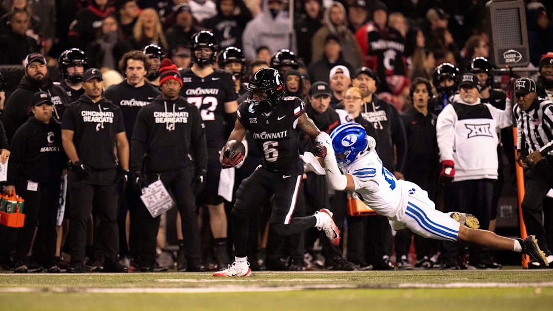 Cincinnati Bearcats running back Evan Pryor (6) brakes a tackle attempt by BYU Cougars linebacker Isaiah Glasker (16) in the fourth quarter of the NCAA football game at Nippert Stadium in Cincinnati on Nov. 22, 2025.