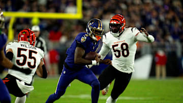 Baltimore Ravens quarterback Lamar Jackson (8) runs downfield for a first down as Cincinnati Bengals linebacker Logan Wilson (55) and Cincinnati Bengals defensive end Joseph Ossai (58) defend in the first quarter of the NFL game at M&T Banks Stadium in Baltimore on Thursday, Nov. 7, 2024.