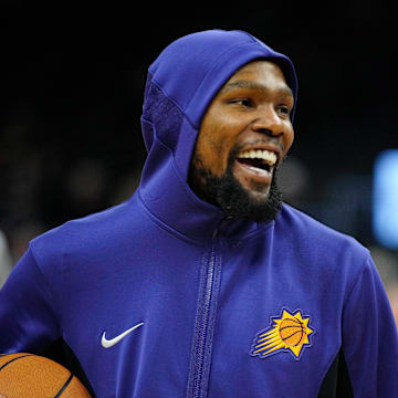 Suns forward Kevin Durant laughs as he takes the court to play the Raptors prior to a game at the Footprint Center.