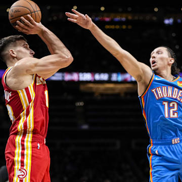 Jan 3, 2024; Atlanta, Georgia, USA; Atlanta Hawks guard Bogdan Bogdanovic (13) shoots the ball over Oklahoma City Thunder forward Lindy Waters III (12) during the second half at State Farm Arena. Mandatory Credit: Dale Zanine-Imagn Images